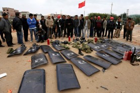 Villagers stand behind shields taken from police injured during clashes at Fuyou village in Jinning county, Kunming