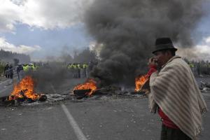 An indigenous protester from the highlands stands at a burning roadblock along the Panamerican Highway during a general strike in the Chasqui area of Ecuador, Thursday, Aug. 13, 2015. A strike by a broad coalition upset with President Rafael Correa virtually paralyzed the capital, provincial cities and stretches of the Panamerican highway. The protesters are indigenous activists, unionists, environmentalists and members of the traditional political opposition. (AP Photo/Dolores Ochoa)